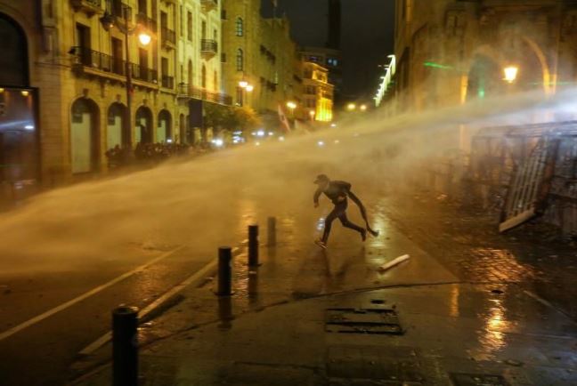 متظاهر يحاول الهرب من مدافع المياه التي يستخدمها الأمن اللبناني لتفريق المحتجين في بيروت. تصوير: عزيز طاهر - رويترز.